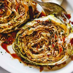 an artichoke is on a white plate with spoons