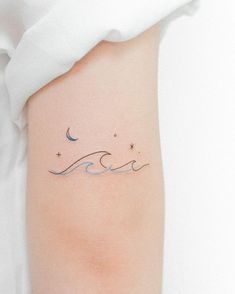 a woman's arm with a wave tattoo on it and stars in the sky