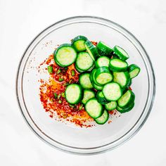 a glass bowl filled with sliced cucumbers and spices