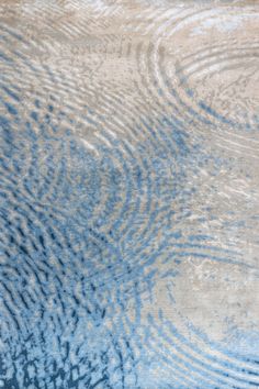 a blue and beige area rug with wavy lines on the ground in front of it