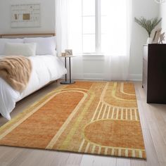 an orange and yellow rug in a white room with a bed, nightstands and window