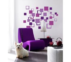 a small white dog sitting on the floor in front of a purple chair and wall