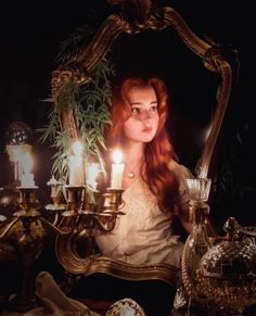 a woman sitting in front of a mirror with candles