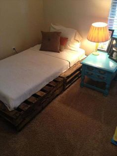 a twin bed made out of pallets in a room with a lamp on the side