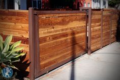 a wooden fence next to a house with a potted plant in the foreground