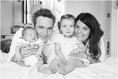 a man, woman and child are laying on a bed with their arms around each other