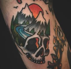 a skull with mountains and trees on it's back half - sleeved tattoo