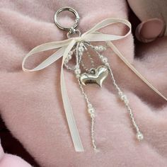 a keychain with pearls and a heart hanging from it's side on a pink blanket