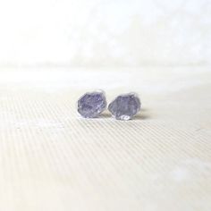 These stud earrings feature genuine Tanzanite gemstones suspended in clear resin for a modern and unique design in the shape faceted gem. Made with hypoallergenic stainless steel posts and including both metal and silicone backings for a secure fit, these earrings are perfect for all-day wear. Measuring 0.27 x 0.24 inches (7mm x 6mm), they offer a subtle statement of elegance, making them a perfect gift for yourself or a loved one. For lasting beauty, avoid cleaning the resin with harsh chemicals or exposing them to excessive heat.  Choose your perfect presentation:       *Elegant earring card: Ideal for showcasing the beauty of the earrings.       *Gift-ready small box: Perfect for presenting the earrings as a thoughtful gift.        *Add a personal message (needs to be marked as a gift) Tanzanite Studs, Earring Card, Faceted Gems, Tanzanite Gemstone, Earring Cards, December Birthstone, Clear Resin, Small Earrings, Raw Stone