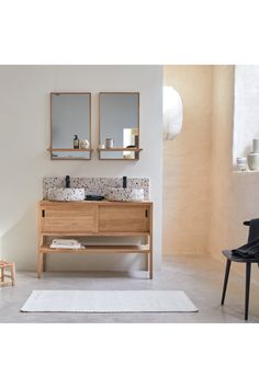 a bathroom vanity with two mirrors above it and a rug on the floor next to it