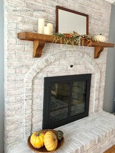 a white brick fireplace with some pumpkins on the mantle