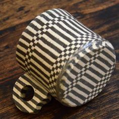 a black and white striped vase sitting on top of a wooden table with a hole in the middle