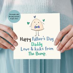 a woman holding up a card that says happy father's day daddy love & kicks from the bump