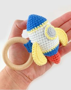 a hand holding a crocheted toy in the shape of a rocket ship