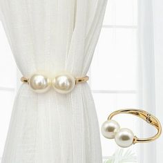 two pearls are attached to the side of a curtain with a gold ring on it