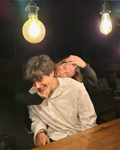 a man and woman sitting at a table in front of some lightbulbs