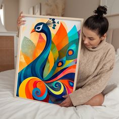 a woman sitting on a bed holding up a colorful peacock art piece in front of her