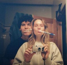 two people taking a selfie in front of a mirror with toothbrushes sticking out of their mouths