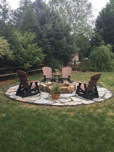 an outdoor fire pit with chairs around it