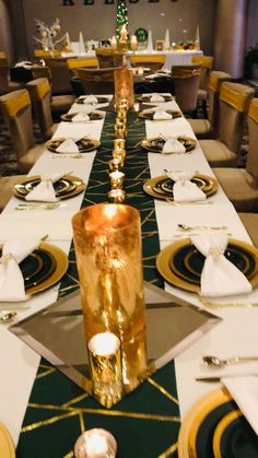 a long table is set with white and gold place settings, silverware, and candles