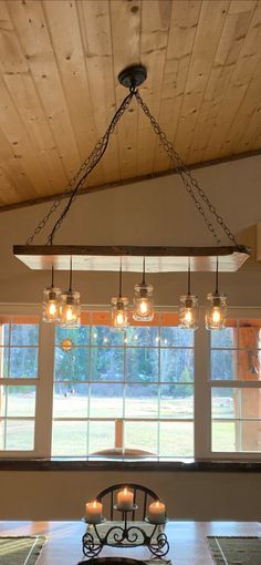 a chandelier hanging from the ceiling over a dining room table with candles on it