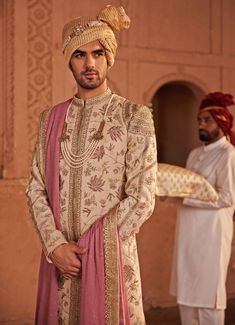 Elevate your traditional style with the luxurious Beige Embroidered Sherwani Set, meticulously crafted from premium silk jacquard. This beige sherwani is adorned with intricate geometric and floral patterns, blending classic artistry with modern elegance. Paired with a matching kurta and pants, it offers a complete look that is both sophisticated and timeless. The ensemble is finished with an embroidered stole in soft pink hues, adding a regal touch to the overall design. Perfect for the groom on their special day, this outfit embodies the essence of tradition and craftsmanship, making it ideal for the modern groom who values both heritage and contemporary style. Composition : Sherwani, Stole, Kurta and Churidar - Silk JacquardCare: Dry Clean Only and Vacuum Storage Delivery : 4-6 weeks as Sherwani For Dark Skin Groom, Groom Sherwani Indian, Festive Beige Embroidered Sherwani, Transitional Beige Sherwani With Intricate Embroidery, Traditional Semi-stitched Cream Sherwani, Festive Semi-stitched Cream Sherwani, Semi-stitched Gold Embroidered Sherwani, Indian Wedding Clothes For Men, Sherwani Groom