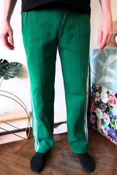 Beautiful Vintage track pants from the late 1980s. Nice green color with white stripes on the sides. Comfortable cotton blend fabric. Regular fit. One zipped side pocket, zipped leg openings. Elasticated waistband, tie band in the waist to adjust the fit. Unisex. For an amazing true vintage street style wear with a simple tee and sneakers! BRAND: Grasshoppers ERA: 1980s COLOUR: Green, white FABRIC: 45% nylon, 37% cotton, 18% viscose SIZE: Vintage size 7, fits best men's size L-XL, can also be wo Casual Green Bottoms With Three Stripes, Green Streetwear Pants With Side Stripes, Green Sweatpants With Side Stripes For Streetwear, Green Side Stripe Pants For Streetwear, Green Pants With Side Stripes For Streetwear, Green Bottoms With Side Stripes For Streetwear, Green Athleisure Bottoms With Side Stripes, Sporty Green Cotton Pants, Green Cotton Sweatpants With Side Pockets