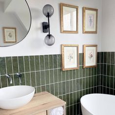 a white bath tub sitting next to a sink in a bathroom under a round mirror