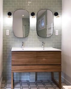 a bathroom with two mirrors above the sink and tiled flooring on the wall behind it