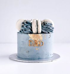 a blue cake with white frosting and two cookies on top that says, dad