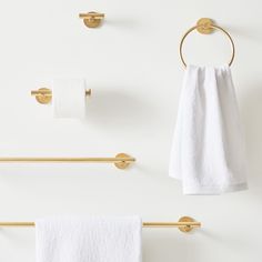 three gold towel racks and two white towels hanging on the wall next to each other