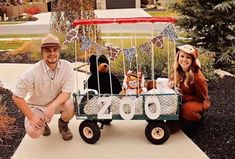 a man and woman are posing in front of a wagon with stuffed animals on it