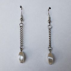 These earrings are attached with silver chain to a silver earring hook. They feature one pearly white bead per earring. These earrings measure approximately 2.3" long. These will look great with your favorite style. All products are made with hypoallergenic materials. Every piece is made by hand and one of a kind. Get them before they're gone. Go to our website https://www.slainte-cheers.com for exclusive pricing. White Pearl Nickel Free Earrings, Metal Drop Earrings With Pearl Charm, Pearl White Dangle Pearl Earrings, Hypoallergenic Dangle Pearl Earrings, White Metal Beaded Earrings, Silver Pearl Long Drop Earrings, Pearl White Metal Earrings With Pearl Drop, Silver Dangle Pearl Earrings, White Metal Beaded Earrings With Ear Wire