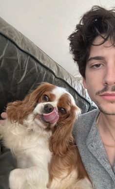 a man is holding a dog in his lap and posing for the camera with it's tongue out