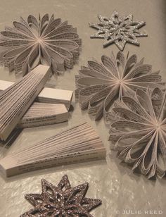 paper flowers and other crafting supplies on a table with glittered papers in the shape of snowflakes