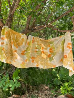 an orange and yellow flowered cloth hanging from a tree