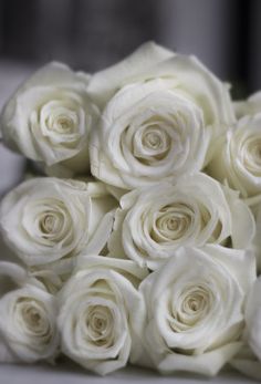 a bouquet of white roses sitting on top of a table