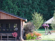 a small wooden shed sitting next to a lush green park filled with flowers and trees