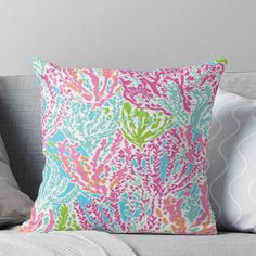 a colorful pillow sitting on top of a couch next to a white wall and pillows