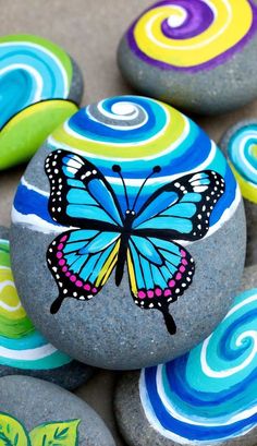 painted rocks with colorful swirls and a butterfly on them