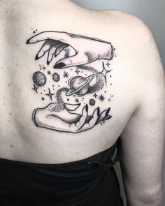 a woman's back with an image of two hands touching each other and planets in the sky