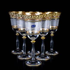 four wine glasses with gold trimmings on them