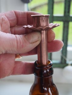 a person holding a small cross on top of a bottle