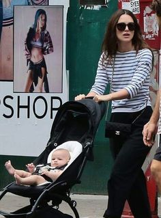 a woman walking down the street with a baby in a stroller next to her