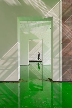 a person is walking in an empty room with green water on the floor and walls