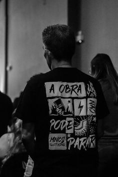 a man wearing a black shirt with white writing on it and people in the background