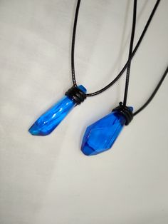 two necklaces with blue glass beads hanging from black cord