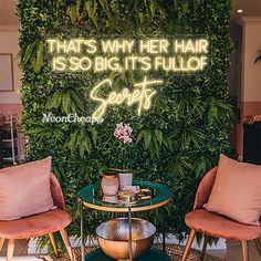 two chairs and a table in front of a green wall with neon words that says, that's why her hair is so big it's full of secrets