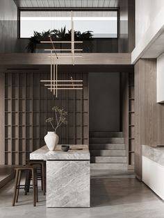 a dining room with marble table and stools in front of the stairs leading up to the second floor