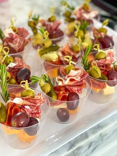 small cups filled with different types of food on top of a glass counter topped with green olives